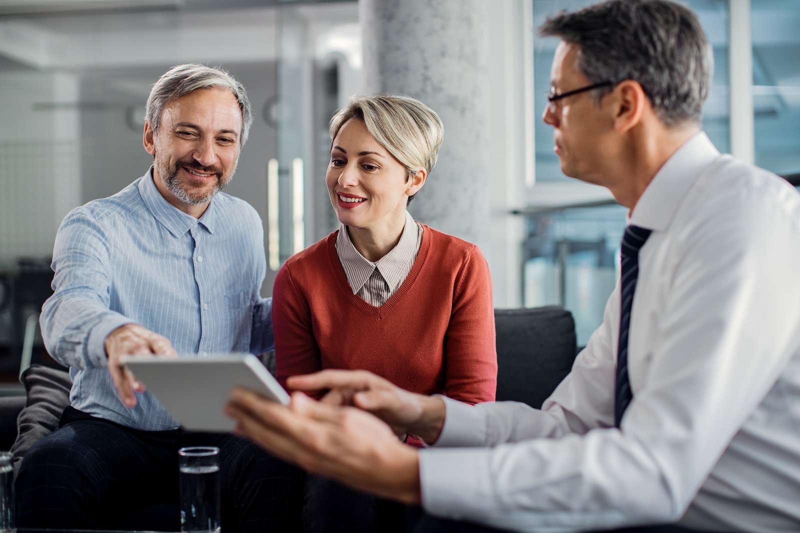 happy-mid-adult-couple-using-touchpad-with-their-financial-consultant-in-the-office-.jpg